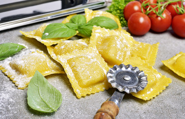 Wall Mural - Ravioli pasta, homemade pasta and pasta roller on a stone background. Italian cuisine, fresh pasta cooking.