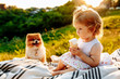 © matilda553 - a little girl with ice cream sitting on a blanket in the Park at sunset. Dog looks at it
