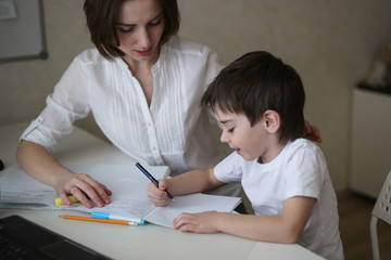 Wall Mural - beautiful mother teaches her son at home at table