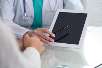 Wall Mural - Doctor and patient, close-up.  Physician pointing into touch pad screen of tablet computer. Medicine, healthcare and helping concept