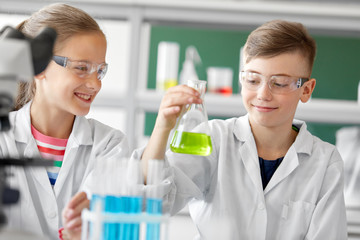 Wall Mural - education, science and children concept - kids with test tubes studying chemistry at school laboratory