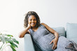 © Cavan Images - Portrait of pregnant woman leaning on sofa against wall at home