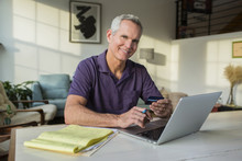 Portrait Of Mature Man Using Laptop Computer While Paying Bills At Home