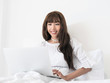 © natsarun - Happy casual beautiful asian woman lying on bed using laptop in bedroom at home