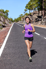 Wall Mural - Running runner woman athlete jogging on nature road in mountains training cardio for marathon run breathing and doing endurance workout. Happy Asian girl working out outside in summer.