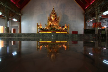 golden color meditating Gautama buddha ststue image with two disciples praying in the front and Bodhi tree in the back. Secred buddhist image in an old wooden temple. peace of mind and soul concepts