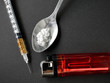 Drug syringe with cooked heroin on black background