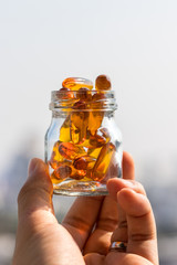 Fish oil capsules in glass bottle on bokeh background, vitamin D supplement, selective focus