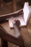 Fototapeta Do akwarium - african education close up - macro photography of a black african school kid hand holding a pencil, inside a classroom in the Gambia, Africa