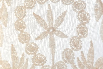 Close-up gentle beige lace with floral motifs on white background.