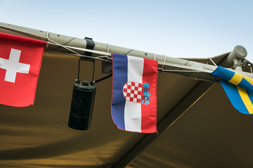 Small croatian flag fluttering on the wind, between two more flags. Croatia is one of the World Cup finalist.