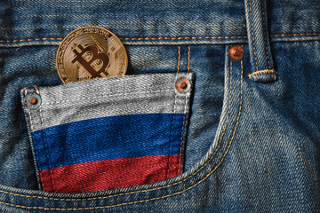 Golden BITCOIN (BTC) cryptocurrency in the pocket of jeans with the flag of Russia