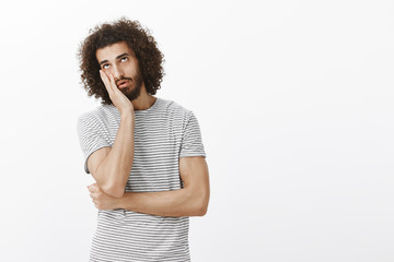 Bored indifferent handsome hispanic man with beard and afro hairstyle, making face palm and looking up with tired and fed up expression, expressing boredom while listening to uninteresting story