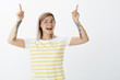 © Cookie Studio - Yes, we did it. Portrait of charming positive and happy cutie in round glasses and braces, raising index fingers and pointing up and smiling broadly, being in great mood after making tattoo
