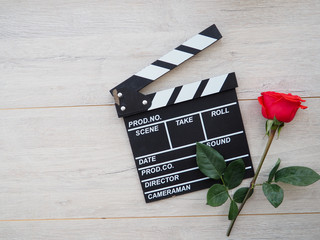 vintage classic clapperboard on brown wooden table whis red roses