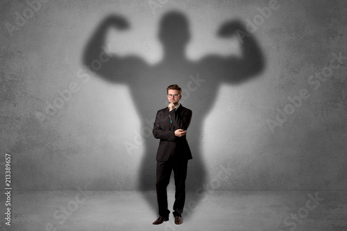 Fotografía Lovely serious businessman standing with a muscular powerful shadow behind his b