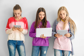 Wall Mural - Cool teenage girls with modern devices on white background