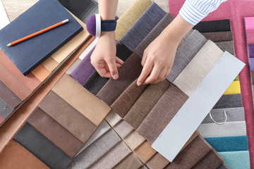 Young woman choosing among upholstery fabric samples, closeup. Interior design