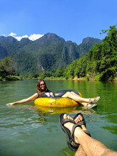 Couple Going Down Nam Song River In A Tube Surrounded By Karst Scenery In Vang Vieng, Vientiane Province, Laos.