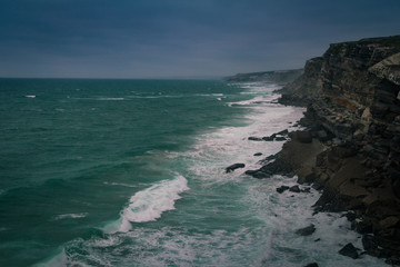 Wall Mural - View of beach  with large waves near Atlantic coast. Large waves of turquoise water crushing on a beach Praia Grande, Sintra, Portugal. Travel concept. Vintage effect. 