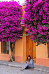 Canvas Print - Young woman reading book on a sidewalk in historic quarter of Colonia del Sacramento, Uruguay