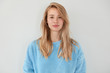 © WHstudio Leushin N - Adorable blonde female with serious expression, dressed in blue sweater, has healthy clean skin, isolated over white background. Pretty woman demonstrates her natural beauty. People and youth