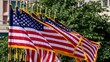 Row of Red white and blue American flags with golden fringe tassels outdoors flapping in the blowing wind with trees in the background