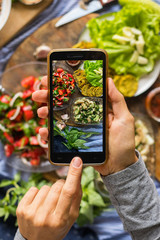 Wall Mural - Smartphone food photography of vegetarian lunch or dinner. Woman hands taking phone photo of food in trendy style for social media or blogging.