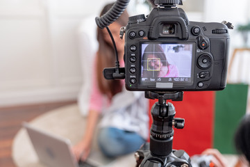 Asian young female blogger recording vlog video with review cloths T-shirt at home online influencer on social media concept.live streaming viral.focus on camera.