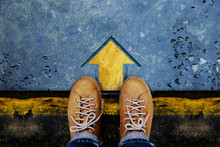 Motivation And Success Concept. Top View Of Male With Leather Shoes Satnding On The Crossroad To Making Decision To Steps Or Stop. Forward Arrow On The Floor As Background