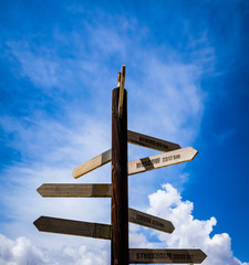 Direction signs on wooden pole framed in a blue sky