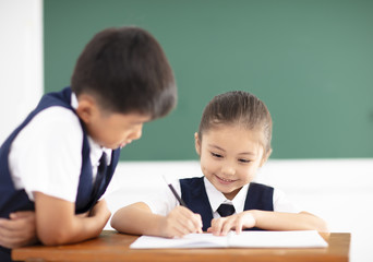 happy little girl writing homework in classroom