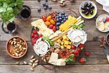 Cheese Platter With Fresh Berries And Nuts On A Rustic Wooden Table. Overhead View.
