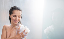 Portrait Of Beaming Woman Rubbing Body With Foam While Standing Under Steam Of Water. Copy Space