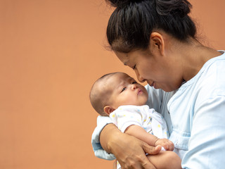 portrait of happy asia mother holding his newborn sweet baby dressed. the mommy embracing her baby w