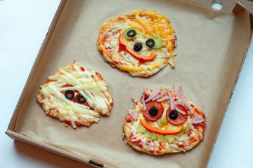 Halloween pizza with monsters, above scene with decor on a craft paper box background, idea for home party food, easy, healthy and delicious fun food party treats for kids