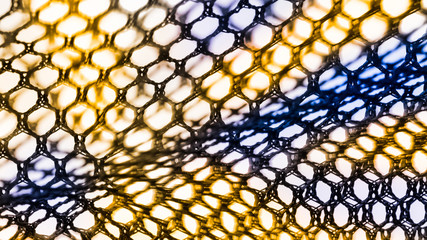 Abstract texture of net with hexagonal cells. Artistic detail of the decorative netting in black, yellow and blue color on white background. Concept of science, research, technology and industry.