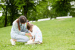 © pressmaster - Little girl crying while sitting on green lawn and her mother comforting her