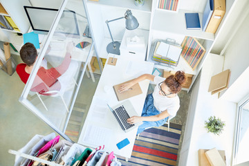 Canvas Print - View of two office managers sitting in open space by their desks and networking