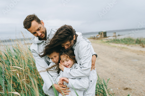 Fotografia Beautiful family portrait dressed in raincoat near the lake