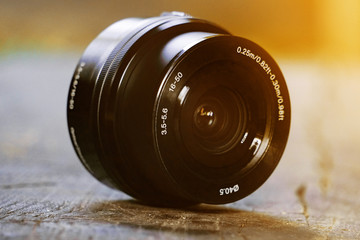 Lens for camera, on an old wooden desk, black lens, photographer