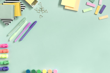 The top view of creative desk with school accessories, notebooks and colorful markers. Pastel color background with copy space for inscription. Back to school.