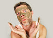 © TheVisualsYouNeed - funny man with green seaweed facial mask on his face posing in front of the mirror mocking on himself using skin care beauty product and cosmetics