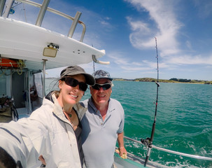 Selfie: father and daughter male and female tourists on fishing charter vessel in Far North District, Northland, New Zealand, NZ