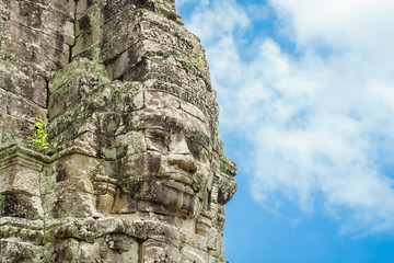 Ancient stone faces at blue sky cloudy of Bayon temple, Angkor Wat, Siam Reap, Cambodia.