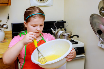 Sweet little cute girl is learning how to make a cake, in the home kitchenlearns to cook a meal in the kitchen