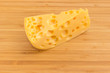 Piece of Swiss-type cheese on bamboo cutting board