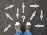 feet standing on asphalt with multitude of arrows in diffrent directions