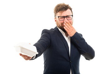 Wall Mural - Portrait of business man holding away bad smelling lunch box.