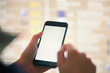 © Bob - Mockup image of female hands holding black mobile phone with blank white screen over flight board in airport terminal